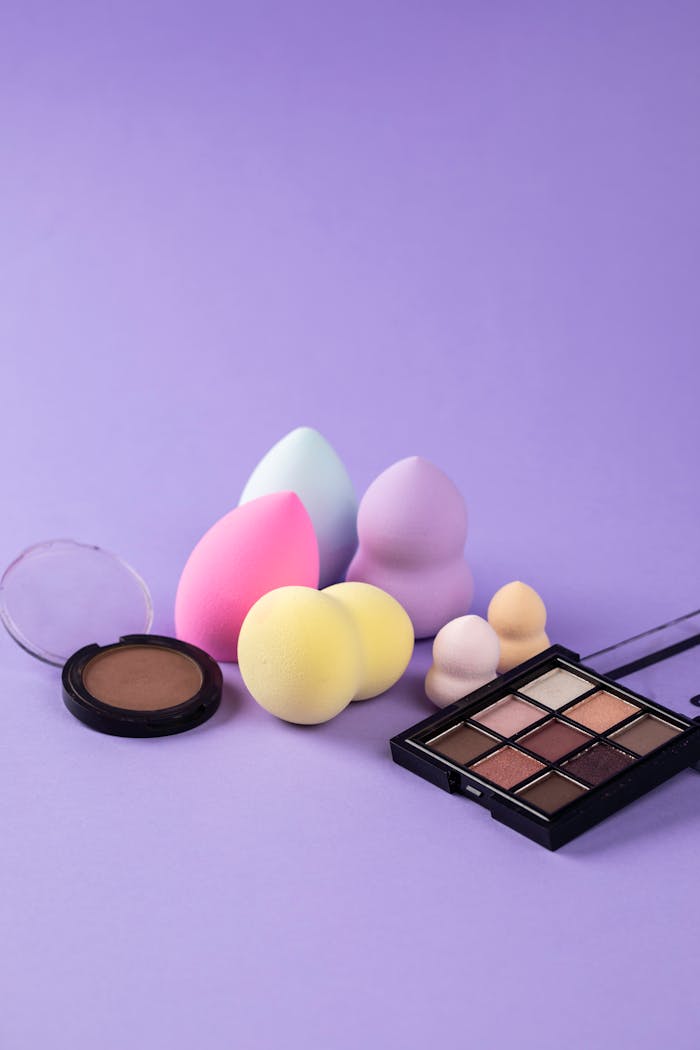 Colorful makeup sponges and cosmetics set against a stylish purple backdrop.